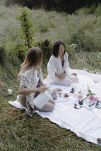 Frau sitzt in weichem Licht mit geschlossenen Augen und Hand auf dem Herzen, während sie ein Ritual zur Verbindung mit ihrem Zyklus und ihrer inneren Ruhe praktiziert.