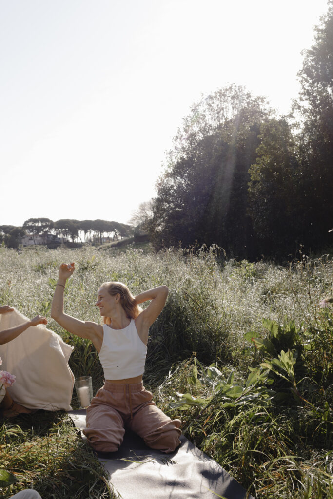 Frau sitzt in weichem Licht mit geschlossenen Augen und Hand auf dem Herzen, während sie ein Ritual zur Verbindung mit ihrem Zyklus und ihrer inneren Ruhe praktiziert.